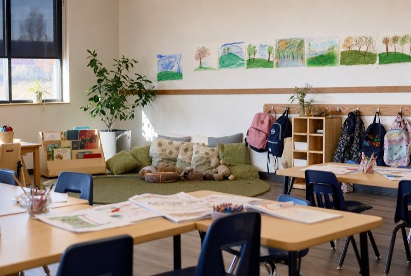 Children’s classroom with workbooks on low tables and a cozy corner for reading
